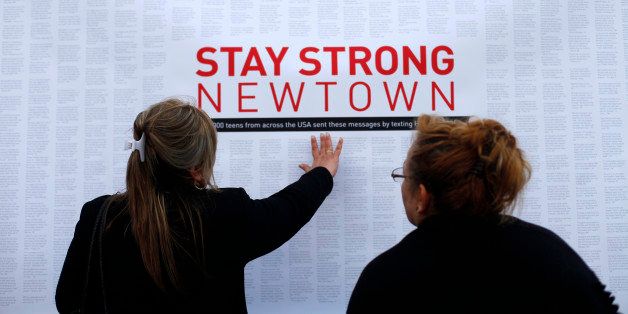 A woman touches a printout of messages from teenagers around the United States at a memorial for the victims of the Sandy Hook Elementary School shooting in Newtown, Connecticut December 18, 2012. REUTERS/Joshua Lott/File Photo