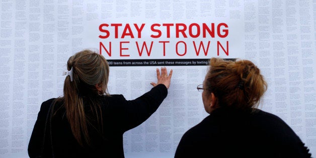 A woman touches a printout of messages from teenagers around the United States at a memorial for the victims of the Sandy Hoo