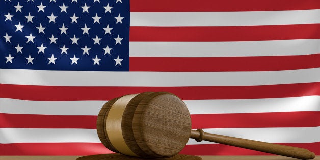 A wooden gavel used in court rulings resting in front of the flag of the United States of America.