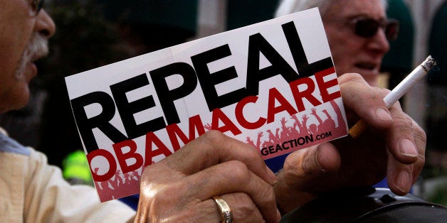 A small group of demonstrators stand outside of of a hotel before former South Carolina Senator Jim DeMint, president of the The Heritage Foundation, speaks at a "Defund Obamacare Tour" rally in Indianapolis, Indiana, U.S. August 26, 2013. REUTERS/Nate Chute/File Photo