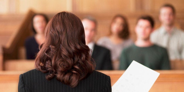 Lawyer holding document and speaking to jury in courtroom