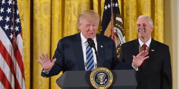 US President Donald Trump speaks, as Vice President Mike Pence watches, before the swearing in of the White House senior staff at the White House on January 22, 2017, in Washington, DC. / AFP / MANDEL NGAN (Photo credit should read MANDEL NGAN/AFP/Getty Images)