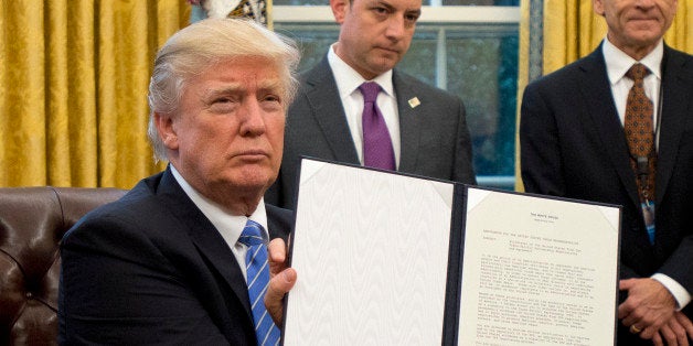 WASHINGTON, DC - JANUARY 23: (AFP OUT) U.S. President Donald Trump shows the Executive Order withdrawing the US from the Trans-Pacific Partnership (TPP) after signing it in the Oval Office of the White House in Washington, DC on Monday, January 23, 2017. The other two Executive Orders concerned a US Government hiring freeze for all departments but the military, and 'Mexico City' which bans federal funding of abortions overseas. (Photo by Ron Sachs - Pool/Getty Images)