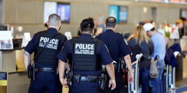 Officers with the U.S. Customs and Border Protection walk past ticket counters during the travel ban at Los Angeles Internati