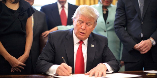 U.S. President Donald Trump signs an executive order cutting regulations, accompanied by small business leaders at the Oval O