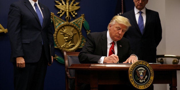 U.S. President Donald Trump signs an executive order he said would impose tighter vetting to prevent foreign terrorists from entering the United States at the Pentagon in Washington, U.S., January 27, 2017. The executive order signed by Trump imposes a four-month travel ban on refugees entering the United States and a 90-day hold on travelers from Syria, Iran and five other Muslim-majority countries. REUTERS/Carlos Barria TPX IMAGES OF THE DAY