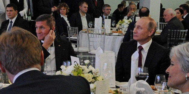 Russian President Vladimir Putin (R) sits next to retired U.S. Army Lieutenant General Michael Flynn (L) as they attend an exhibition marking the 10th anniversary of RT (Russia Today) television news channel in Moscow, Russia, December 10, 2015. Picture taken December 10, 2015. Sputnik/Mikhail Klimentyev/Kremlin via REUTERS ATTENTION EDITORS - THIS IMAGE WAS PROVIDED BY A THIRD PARTY. EDITORIAL USE ONLY. TPX IMAGES OF THE DAY