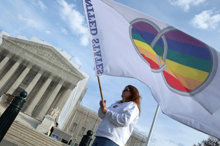 WASHINGTON, DC - NOVEMBER 30: Same-sex marriage proponent Kat McGuckin of Oaklyn, New Jersey, holds a gay marriage pride flag while standing in front of the Supreme Court November 30, 2012 in Washington, DC. With the Supreme Court building draped in a photo-realistic sheet during a repair and preservation project, the justices met today to consider hearing several cases dealing with the rights of gay couples who are married, want to get married or are in domestic partnerships. (Photo by Chip Somodevilla/Getty Images)