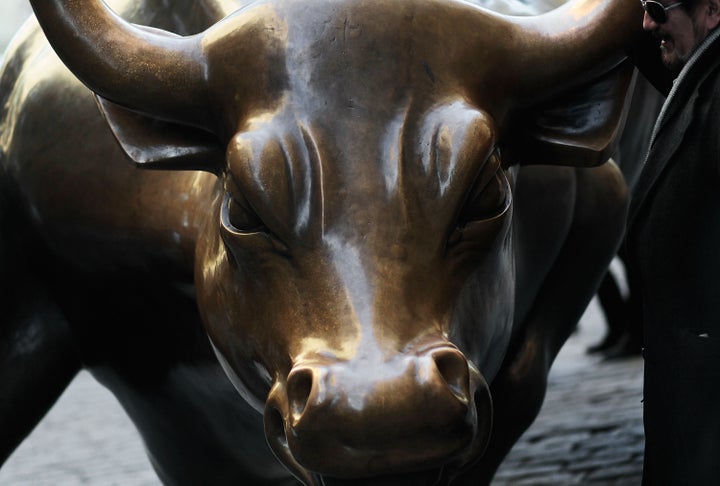NEW YORK - NOVEMBER 02: A man stands next to the bronze bull symbolizing financial markets near Wall Street in lower Manhatt