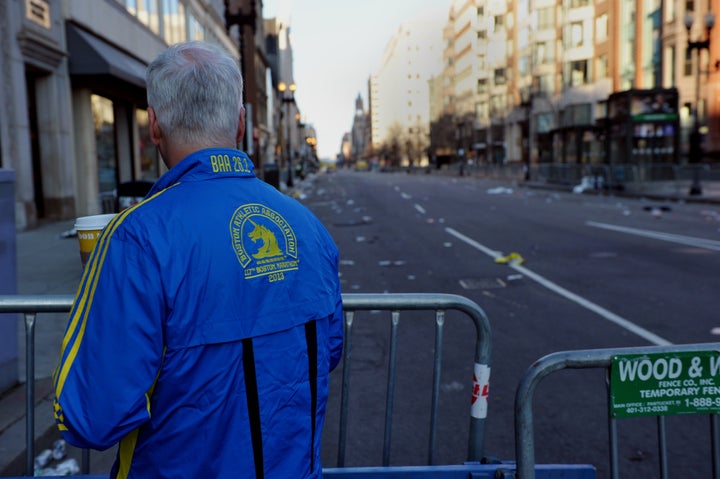 A man who ran in the Boston Marathon looks down a closed-off Boylston Street April 16, 2013 in Boston, Massachusetts, in the aftermath of two explosions that struck near the finish line of the Boston Marathon April 15. A massive probe was underway Tuesday after two bombs struck the Boston Marathon, killing at least three and wounding more than 100. Monday's blasts near the finishing line raised fears of a terrorist attack more than a decade after nearly 3,000 people were killed in suicide airliner strikes on New York, Washington and Pennsylvania on September 11, 2001. US President Barack Obama went on national television to warn against 'jumping to conclusions' but a senior White House official, speaking on condition of anonymity, said such an attack was 'clearly an act of terror.' AFP PHOTO/Stan HONDA (Photo credit should read STAN HONDA/AFP/Getty Images)