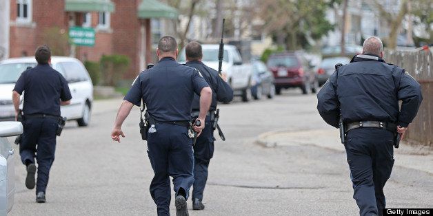 WATERTOWN, MA - APRIL 19: Police run down the street towards Willow Park during the ongoing manhunt for a suspect in the terrorist bombing of the 117th Boston Marathon earlier this week. Watertown is on lockdown following a chase and shootout in the area last night. (Photo by David L. Ryan/The Boston Globe via Getty Images)