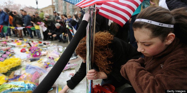 BOSTON, MA - APRIL 20: People gather at a makeshift memorial for victims near the site of the Boston Marathon bombings a day