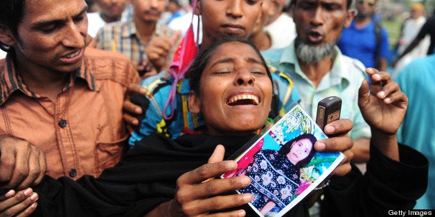 A relative of a missing Bangladeshi garment worker reacts as she gathers at a graveyard for victims of the garment factory collapse in Dhaka on May 1, 2013. Tens of thousands of Bangladeshis joined May Day protests Wednesday to demand the execution of textile bosses over the collapse of a factory complex, as rescuers warned the final toll could be more than 500. AFP PHOTO/Munir uz ZAMAN (Photo credit should read MUNIR UZ ZAMAN/AFP/Getty Images)