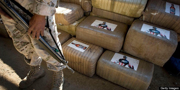 A Mexican soldier stands guard next to packages of marijuana found at a warehouse in Tijuana, Mexico, on Wednesday, Nov. 16, 2011. Approximately 17 tons of marijuana were discovered in a cross-border tunnel that appears to be one of the most significant drug smuggling passages found between the U.S. and Mexico. Photographer: David Maung/Bloomberg via Getty Images