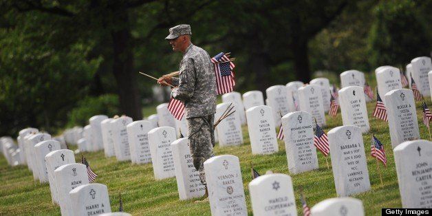 A member of the Third US Infantry Regiment, The Old Guard, places flags in front of graves at Arlington National Cemetery on May 23, 2013 in Arlington, Virginia ahead of Memorial Day. Memorial Day is in honor of those who died while serving in the armed forces of the US. AFP PHOTO/Mandel NGAN (Photo credit should read MANDEL NGAN/AFP/Getty Images)
