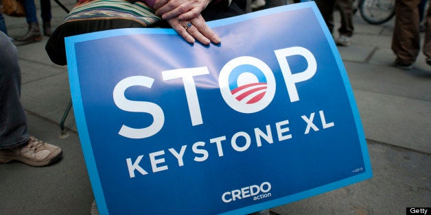 An environmental activist holds a sign in Bryant Park, protesting the proposed Keystone XL pipeline, May 13, 2013 in New York. The group marched through midtown to rally outside the Waldorf Astoria hotel where President Obama was attending a fundraiser. AFP PHOTO/Don Emmert (Photo credit should read DON EMMERT/AFP/Getty Images)