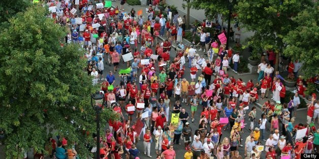 Helen Smith, a retired schoolteacher from Wayne County, North Carolina, holds up handcuffs during a 'Moral Monday' demonstration on Monday, July 29, 2013, in Raleigh. (Al Drago/Raleigh News & Observer/MCT via Getty Images)