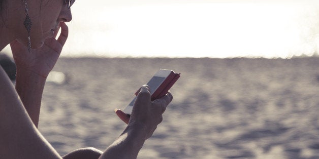 young girl on the beach, typing os smartphone