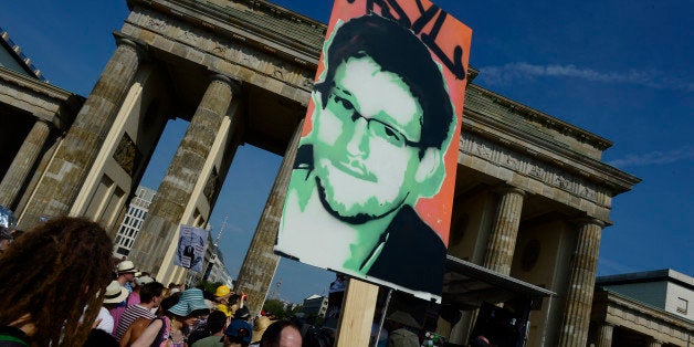 Demonstrators hold up a placard in support of former US agent of the National Security Agency, Edward Snowden in front of Berlin's landmark Brandenburg Gate as they take part in a protest against the US National Security Agency (NSA) collecting German emails, online chats and phone calls and sharing some of it with the country's intelligence services in Berlin on July 27, 2013. AFP PHOTO / JOHN MACDOUGALL (Photo credit should read JOHN MACDOUGALL/AFP/Getty Images)