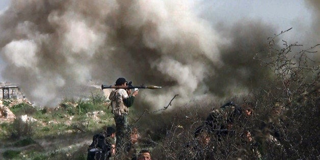 An image grab taken from a video shows opposition fighter holding a rocket propelled grenade (RPG) as his fellow comrades take cover from an attack by regime forces on August 26, 2013 during clashes over the strategic area of Khanasser, situated on the only road linking Aleppo to central Syria. Rebels had in recent days captured several villages in Aleppo province, much of which is already in the hands of anti-regime fighters, before taking Khanasser, situated on the highway to Hama in central Syria, thus cutting the army's only supply route to the northern province. AFP PHOTO / SALAH AL-ASHKAR (Photo credit should read SALAH AL-ASHKAR/AFP/Getty Images)
