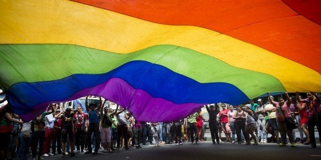 People wave a huge rainbow flag during the 35th Gay Pride Parade in downtown Caracas on June 30, 2013. AFP PHOTO / Leo RAMIR