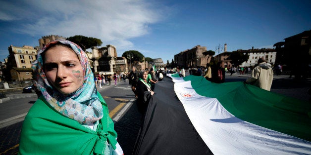 Demonstrators hold a large Syrian National Coalition flag as they rally against Syrian President Bashar al-Assad in downtown Rome on April 13, 2013. At least 54 people were killed in violence across Syria on April 13, according to the Britain-based Syrian Observatory for Human Rights, which relies on a network of activists and medics for its information. AFP PHOTO / Filippo MONTEFORTE (Photo credit should read FILIPPO MONTEFORTE/AFP/Getty Images)