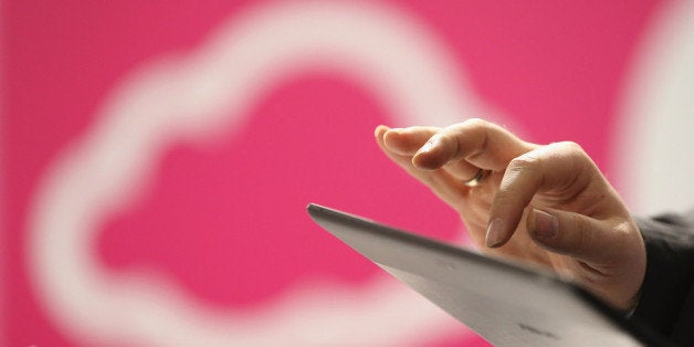 HANOVER, GERMANY - MARCH 05: A visitor tries out a tablet computer next to a cloud computing and technology symbol at the Deutsche Telekom stand at the 2013 CeBIT technology trade fair on March 5, 2013 in Hanover, Germany. CeBIT will be open March 5-9. (Photo by Sean Gallup/Getty Images)