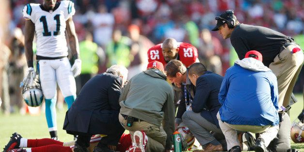 SAN FRANCISCO, CA - NOVEMBER 10: Head Coach Jim Harbaugh of the San Francisco 49ers and the medical staff check out Eric Reid #35 after he received a concussion during the game against the Carolina Panthers at Candlestick Park on November 10, 2013 in San Francisco, California. The Panthers defeated the 49ers 10-9. (Photo by Michael Zagaris/San Francisco 49ers/Getty Images) 