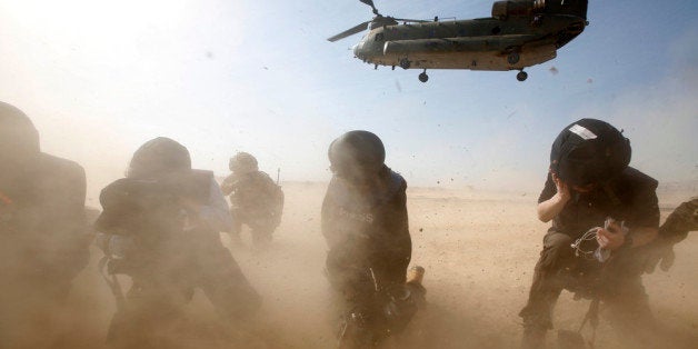 HELMAND, AFGHANISTAN - DECEMBER 16: Members of the media try to protect themselves from dust blown up by a British forces transport helicopter as it lands at the forward operating base Sterga II on December 16, 2013 in Helmand Province, Afghanistan. (Lefteris Pitarakis - Pool/Getty Images)