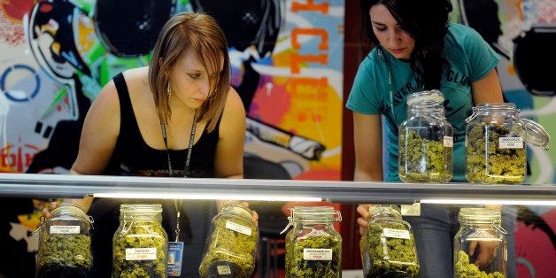 DENVER, CO - JANUARY 1: Brittany Zewe, left, and Jess Vanderpool take jars of different strains of marijuana off the counter between customers at Denver Kush Club in Denver, Colorado on January 1, 2014. The first legal sales of marijuana in the world took place in Colorado on Wednesday morning. (Photo by Seth McConnell/The Denver Post via Getty Images)