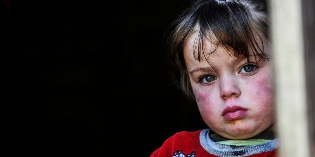 A Syrian refugee child looks out from a shelter in Hatay, Turkey, on January 20, 2014. Representatives of Syrian President Bashar al-Assad, a deeply divided opposition, world powers and regional bodies started a long-delayed peace conference aimed at bringing an end to a nearly three-year civil war. AFP PHOTO/OZAN KOSE (Photo credit should read OZAN KOSE/AFP/Getty Images)