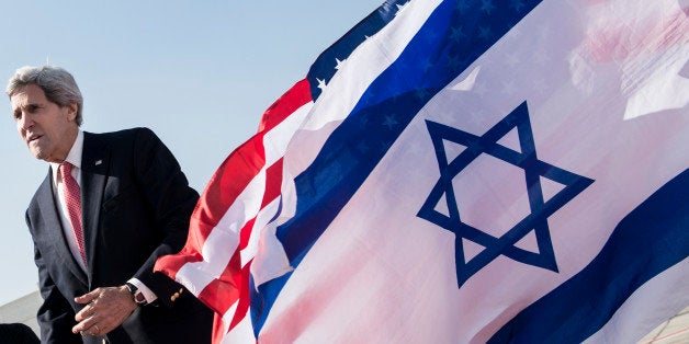 US Secretary of State John Kerry walks past American (back) and Israeli flags at Ben Gurion International Airport in Tel Aviv