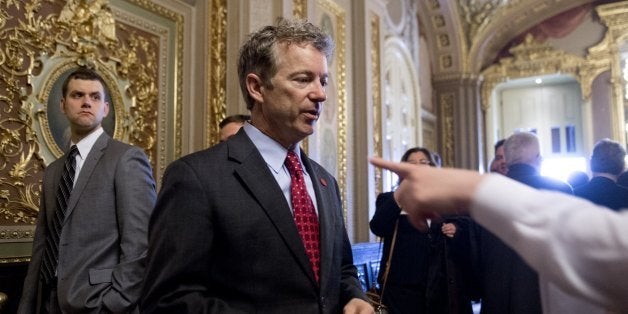 US Republican Senator Rand Paul of Kentucky talks with a staff member as he walks to participate in a cloture vote to end deb