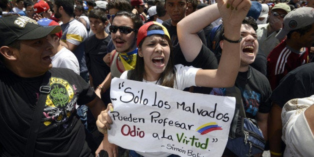 Students shout slogans during an opposition demo against the government of Venezuelan President Nicolas Maduro, in Caracas on February 12, 2014. Unidentified assailants on a motorcycle fired into a crowd of anti-government protesters, leaving at least two people wounded and a pro-government man dead. AFP PHOTO / JUAN BARRETO (Photo credit should read JUAN BARRETO/AFP/Getty Images)