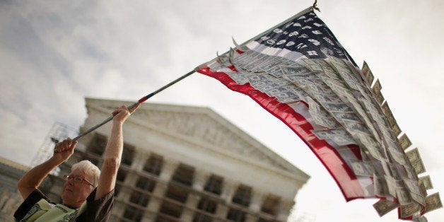 WASHINGTON, DC - OCTOBER 08: David Barrows, of Washington, DC, waves a flag with corporate logos and fake money during a rally against money in politics outside the Supreme Court October 8, 2013 in Washington, DC. On Tuesday, the Supreme Court heard oral arguments in McCutcheon v. Federal Election Committee, a first amendment case that will determine how much money an individual can contribute directly to political campaigns. (Photo by Chip Somodevilla/Getty Images)