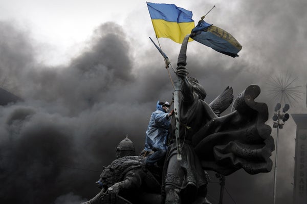 <br>An anti-government protester sits on the Founders of Kiev monument during clashes with riot police in central Kiev on Feb