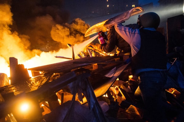 <br>Anti-government protesters stand behing their burning barricades during clashes with police in the center of Kiev on Feb.