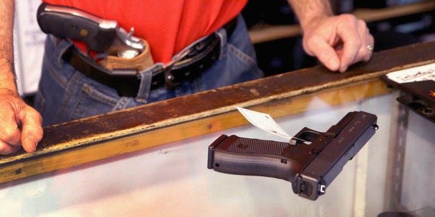 TINLEY PARK, IL - FEBRUARY 13: Dan Egar helps a customer shop for a handgun on February 13, 2014 in Tinley Park, Illinois. Nationwide, sales of guns and ammunition have dropped about 50 percent from the same period last year when dealers had difficulty keeping their stores stocked as customers bought up supplies fearing increased regulation and restrictions after a series highly publicized shootings. (Photo by Scott Olson/Getty Images)