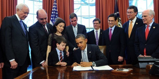 US President Barack Obama is watched by Gabriella Miller's family (L) and lawmakers as he signs the Gabriella Miller Kids First Research Act into law in the Oval Office at the White House in Washington, DC, on April 3, 2014. The legislation, named in memory of 10-year-old children's health research advocate Gabriella Miller from Virginia, who recently died of brain cancer, redirects taxpayer dollars from political party conventions and instead uses funds for pediatric disease research. AFP PHOTO/Jewel Samad (Photo credit should read JEWEL SAMAD/AFP/Getty Images)