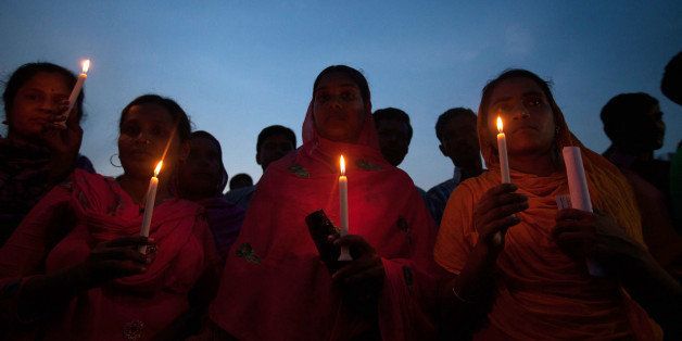 Bangladeshi garment workers and relatives of victims of the Rana Plaza building collapse hold candles during a memorial at the site of the Rana Plaza garment factory building collapse in Savar, on the outskirts of Dhaka on October 24, 2013, the six-month anniversary of the disaster. Relatives of the 1,135 people who lost their lives when the Rana Plaza complex collapsed on April 24 also said they had still to receive any compensation for their loss as they rallied at the site of the tragedy. AFP PHOTO/ SUVRA KANTI DAS (Photo credit should read SUVRA KANTI DAS/AFP/Getty Images)