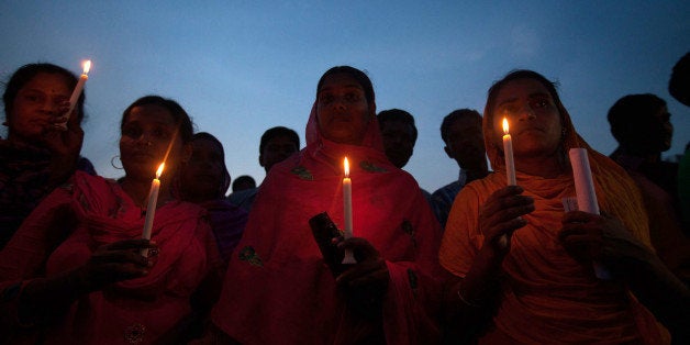 Bangladeshi garment workers and relatives of victims of the Rana Plaza building collapse hold candles during a memorial at th