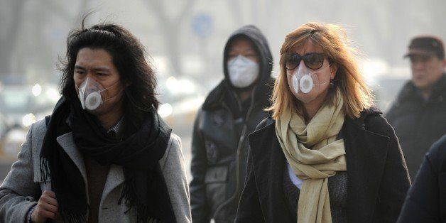 People wearing face masks walk along a street in Beijing on January 16, 2014. China's capital was shrouded in thick smog on January 16, cutting visibility down to a few hundred metres as a count of small particulate pollution reached more than 20 times recommended levels. AFP PHOTO / WANG ZHAO (Photo credit should read WANG ZHAO/AFP/Getty Images)