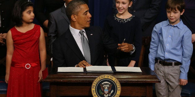 WASHINGTON, DC - JANUARY 16: U.S. President Barack Obama signs a series of executive orders about the administration's new gun law proposals as children who wrote letters to the White House about gun violence, (L-R) Hinna Zeejah, Taejah Goode, Julia Stokes and Grant Fritz, look on in the Eisenhower Executive Office building, on January 16, 2012 in Washington, DC. One month after a massacre that left 20 school children and 6 adults dead in Newtown, Connecticut, the president unveiled a package of gun control proposals that include universal background checks and bans on assault weapons and high-capacity magazines. (Photo by Mark Wilson/Getty Images)