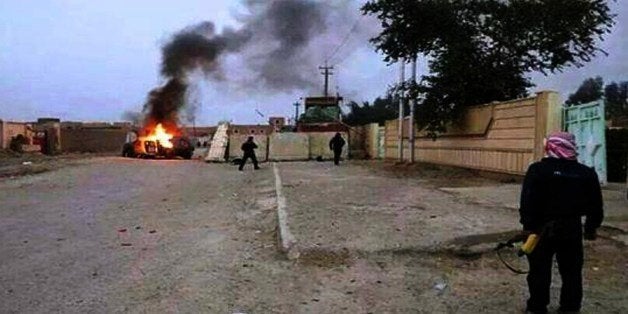 A picture taken with a mobile phone shows an armed man watching as a vehicle, reportedly belonging to Iraqi security forces, is seen in flames on June 10, 2014 in Mosul, some 370 kms north from the Iraqi capital Baghdad. Some 500,000 Iraqis have fled their homes in Iraq's second city Mosul after Jihadist militants took control, fearing increased violence, the International Organization for Migration said. AFP PHOTO/STR (Photo credit should read STR/AFP/Getty Images)