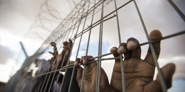 African asylum seekers, who entered Israel illegally via Egypt, lean at the fence of the Holot detention centre in Israel's southern Negev Desert, on February 17, 2014 as they join other migrants who came to protest outside the detention facility. The Israeli government has opened last year the sprawling Holot detention facility to house both new entrants and immigrants already in the country deemed to have disturbed public order. Tens of thousands of migrants, mostly Eritrean and Sudanese, have been staging mass demonstrations in the country against moves by the Israeli authorities to track them down and deport them, or throw them into detention facilities without trial. AFP PHOTO/JACK GUEZ (Photo credit should read JACK GUEZ/AFP/Getty Images)