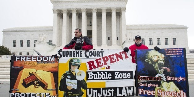 Pro-life demonstrators stand outside the US Supreme Court following oral arguments in the case of McCullen v. Coakley, dealing with a Massachusetts law imposing a 35-foot buffer zone around abortion clinics for demonstrations and protests, in Washington, DC, January 15, 2014. An anti-abortion protestor, Eleanor McCullen of Newton, Massachusetts, argues that the 2007 state law restricts her free speech rights under the First Amendment, while the state and Planned Parenthood argue they provide protection for individuals going to the clinics and provide a way to maintain public safety. AFP PHOTO / Saul LOEB (Photo credit should read SAUL LOEB/AFP/Getty Images)