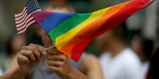 MIAMI, FL - JULY 02: A protester holds an American flag and rainbow flag in front of the Miami-Dade Courthouse to show his support of the LGBTQ couples inside the courthouse were asking the state of Florida to recognize their marriage on July 2, 2014 in Miami, Florida. Six couples that identify as Lesbian, Gay, Bisexual, Transgender and Queer (LGBTQ) are in court asking that their same-sex marriage be recognized in the state of Florida. (Photo by Joe Raedle/Getty Images)