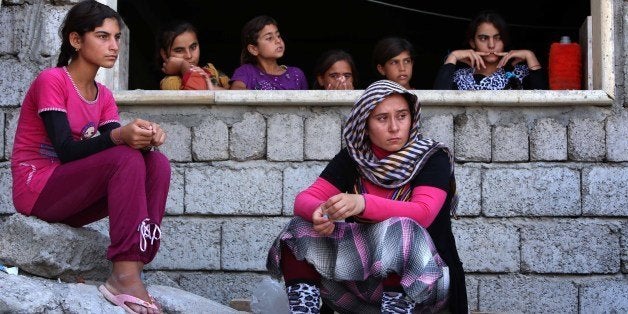 Iraqi Yazidi women who fled the violence in the northern Iraqi town of Sinjar, sit at a school where they are taking shelter in the Kurdish city of Dohuk in Iraq's autonomous Kurdistan region, on August 5, 2014. Islamic State (IS) Sunni jihadists ousted the Peshmerga troops of Iraq's Kurdish government from the northern Iraqi town of Sinjar, forcing thousands of people from their homes. The Yazidis, are a small community that follows a 4,000-year-old faith and have been repeatedly targeted by jihadists who call them 'devil-worshipers' because of their unique beliefs and practices. AFP PHOTO/SAFIN HAMED (Photo credit should read SAFIN HAMED/AFP/Getty Images)