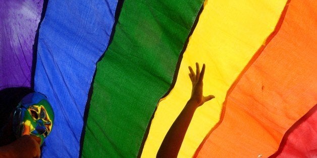 Members and supporters of the lesbian, gay, bisexual, transgender (LGBT) community walk with a rainbow...