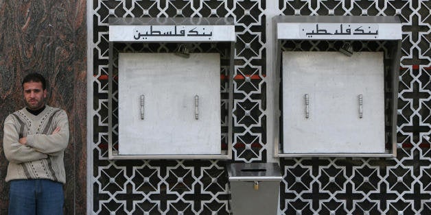 A Palestinian man stands outside a bank with locked ATMs in Gaza city on December 6, 2008. Banks in the Gaza Strip closed the